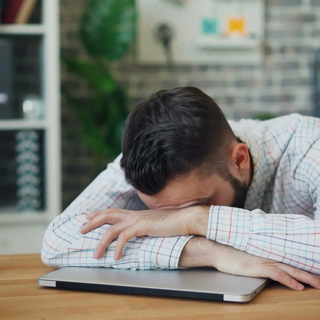 Homme épuisé en journée, illustrant la fatigue diurne causée par les signes de l'apnée du sommeil.